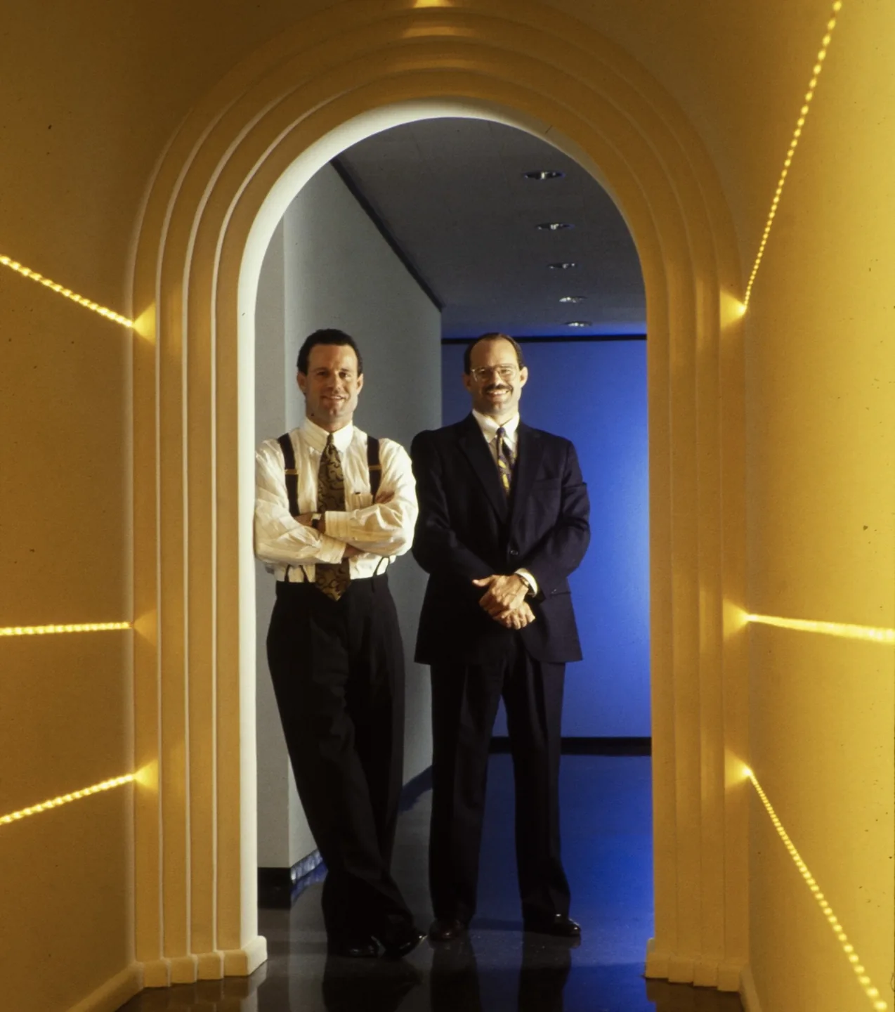 An archival photograph of two colleagues standing beneath an illuminated archway