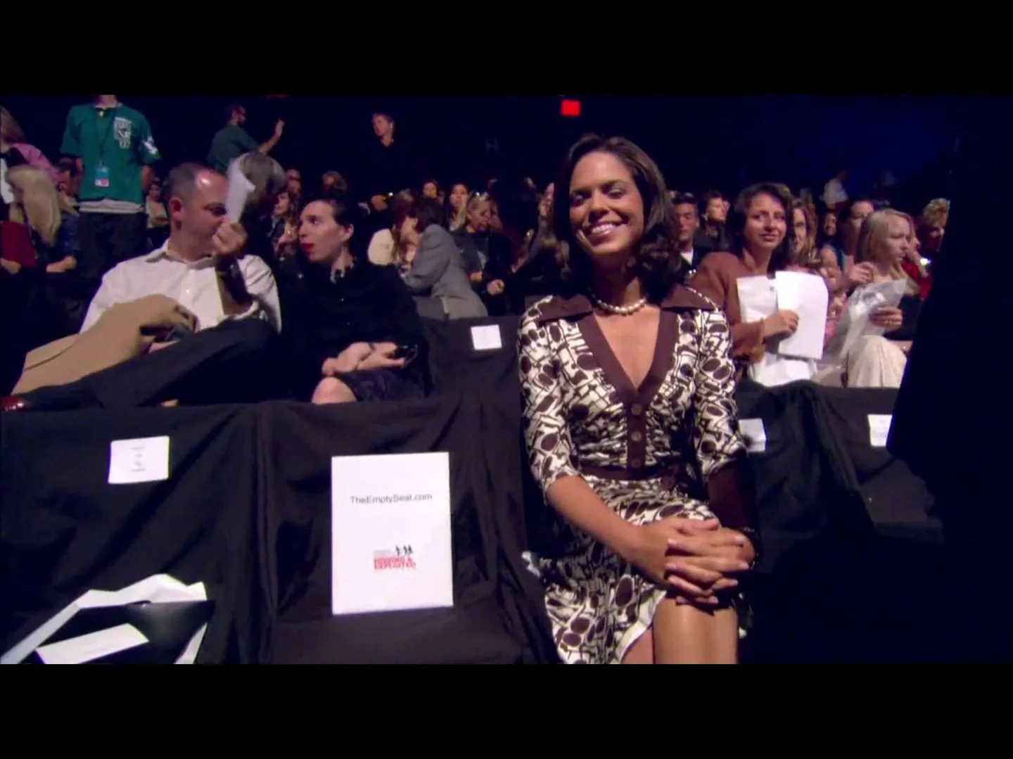 Woman smiling at event with reserved seats.